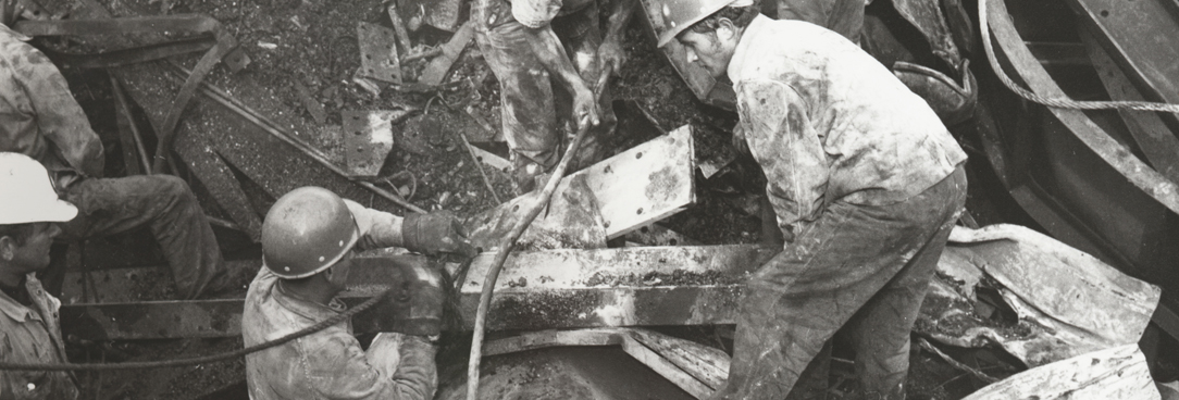 Black and white photo, rescuers searching through the rubble for survivors after the bridge collapse.